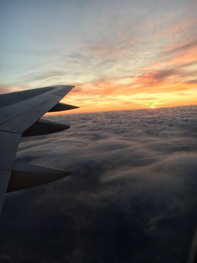 A wing of an airplane flying above clouds

Description automatically generated