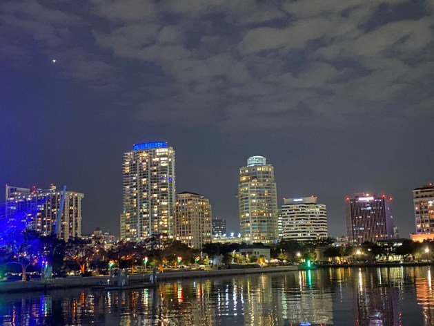 A city skyline at night with a body of water

Description automatically generated