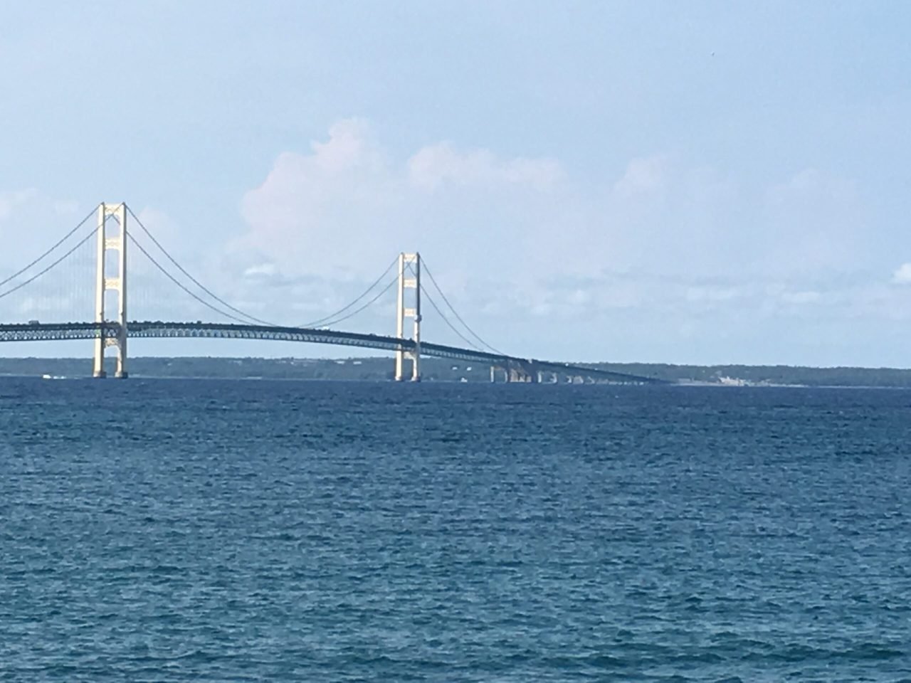 A bridge over water with a blue sky
Description automatically generated