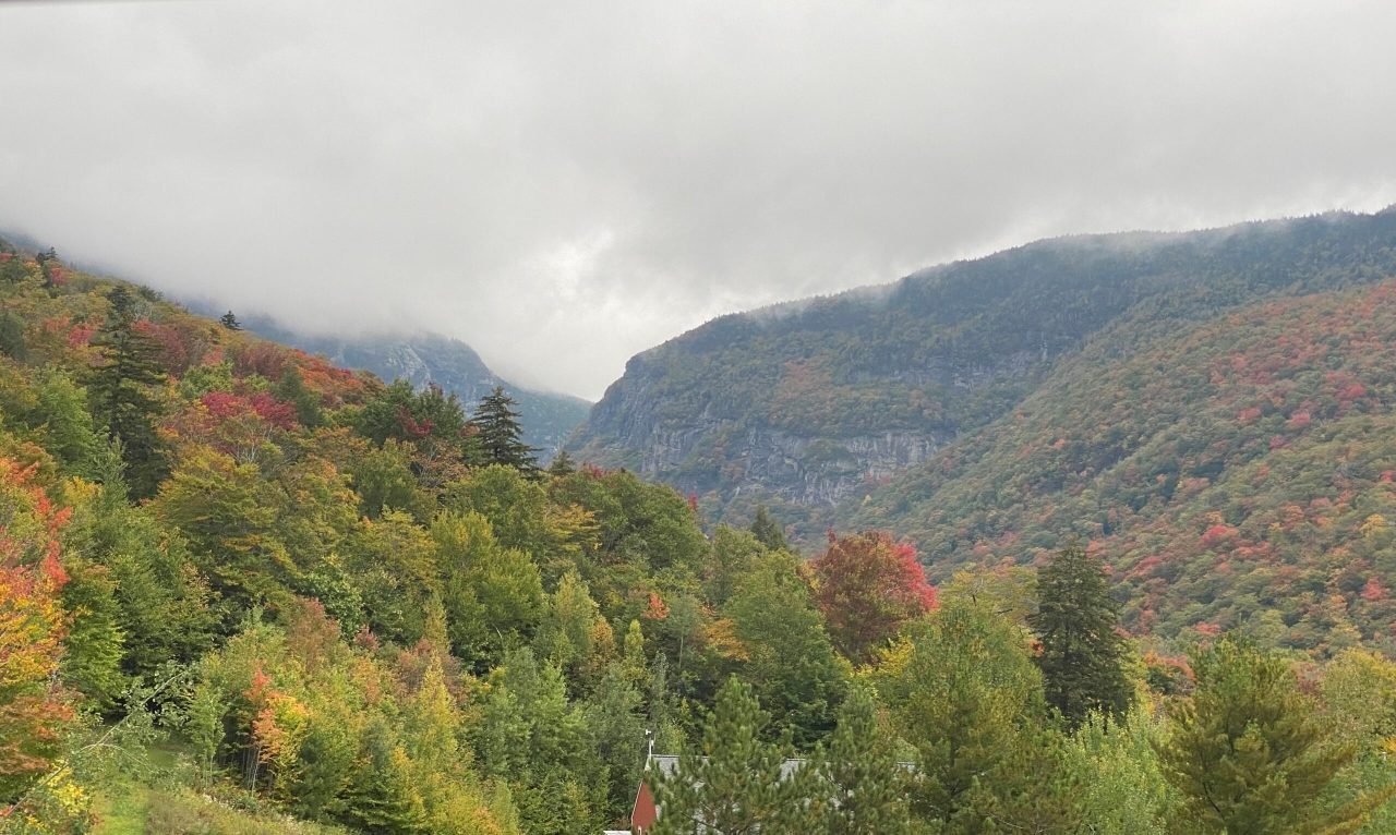 A mountain range with trees and clouds
Description automatically generated