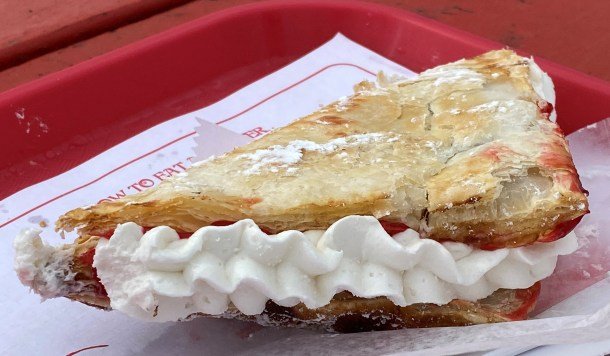 A slice of pie with whipped cream on top
Description automatically generated