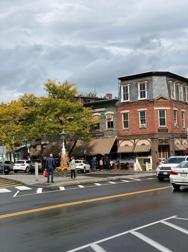 A street with cars and people on it
Description automatically generated