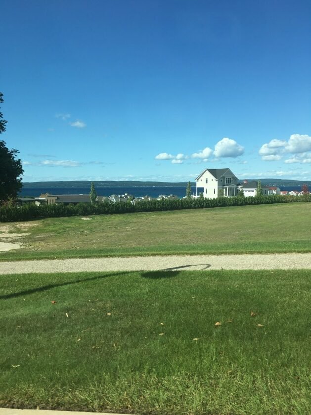 green field with homes on a bluff overlooking little traverse bay
