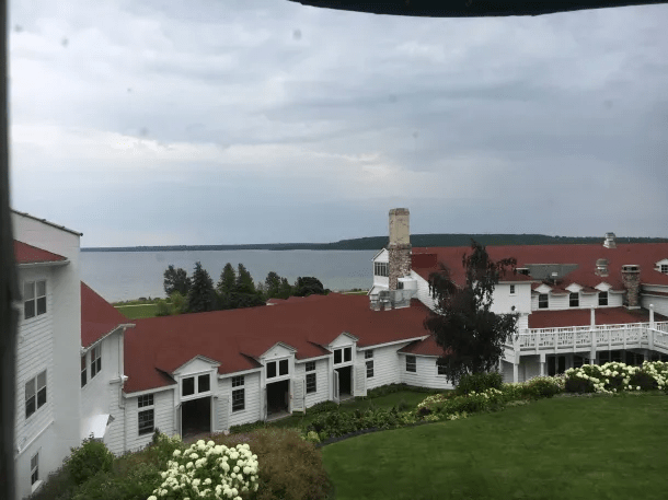 A large white building with a red roof and a lawn and a body of water

Description automatically generated